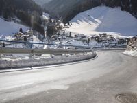 a person is riding their bike down the snow covered road of a mountain village in the winter
