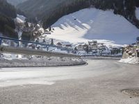 a person is riding their bike down the snow covered road of a mountain village in the winter
