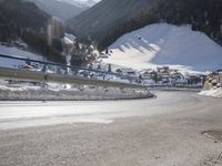 a person is riding their bike down the snow covered road of a mountain village in the winter