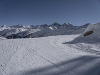 a snowy ski slope on which the skier is going down the hill and into the mountains