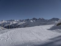 a snowy ski slope on which the skier is going down the hill and into the mountains