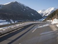 a car travels down the street through the mountains in wintertime near snowy slopes and snow