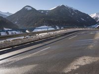 a car travels down the street through the mountains in wintertime near snowy slopes and snow