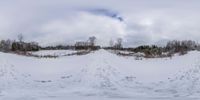 a panorama photo of snow on a road in wintertime in the countryside with trees and sky