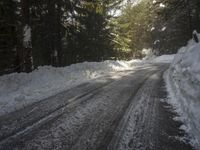 the trees are along the side of this snow - covered road as it is cleared