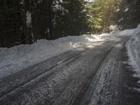 the trees are along the side of this snow - covered road as it is cleared