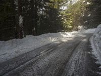 the trees are along the side of this snow - covered road as it is cleared