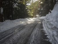 the trees are along the side of this snow - covered road as it is cleared
