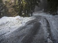 the trees are along the side of this snow - covered road as it is cleared