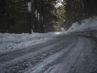 the trees are along the side of this snow - covered road as it is cleared