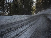 the trees are along the side of this snow - covered road as it is cleared