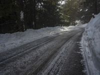 the trees are along the side of this snow - covered road as it is cleared