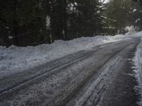the trees are along the side of this snow - covered road as it is cleared