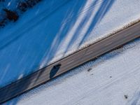 a car drives on the snow covered road near trees and bushes in a winter landscape