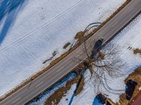 a car drives on the snow covered road near trees and bushes in a winter landscape