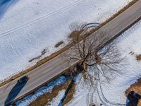 a car drives on the snow covered road near trees and bushes in a winter landscape