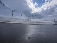 this is a road with snow on the side of it and a mountain in the background