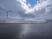 this is a road with snow on the side of it and a mountain in the background