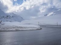 this is a road with snow on the side of it and a mountain in the background