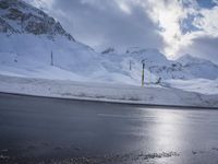 this is a road with snow on the side of it and a mountain in the background