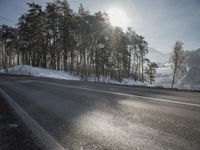 the road has been snow covered, so the sun is setting in the distance below the tree line