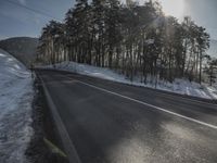 the road has been snow covered, so the sun is setting in the distance below the tree line