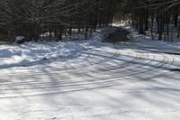 a snow covered road in winter with tracks in it and trees on the side of the road