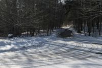 a snow covered road in winter with tracks in it and trees on the side of the road