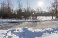 a road is covered in white snow in the middle of a wooded area with tall trees