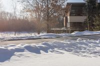 snow piled up on the side of the road next to a building in the distance