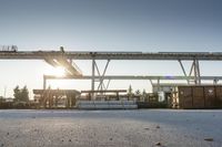 a road under an overpass with snow on the ground and buildings below and in the background