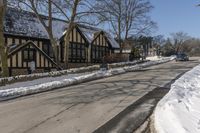 a road with several houses and no vehicles in the middle of it with some snow on the ground