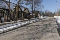 a road with several houses and no vehicles in the middle of it with some snow on the ground