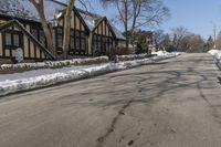 a road with several houses and no vehicles in the middle of it with some snow on the ground