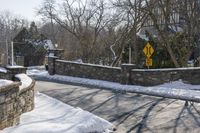 a road blocked by rock walls and trees in winter time in a town area with snow