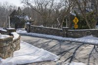 a road blocked by rock walls and trees in winter time in a town area with snow