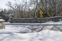 a road blocked by rock walls and trees in winter time in a town area with snow