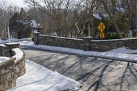 a road blocked by rock walls and trees in winter time in a town area with snow