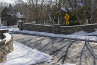 a road blocked by rock walls and trees in winter time in a town area with snow