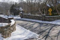 a road blocked by rock walls and trees in winter time in a town area with snow