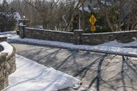 a road blocked by rock walls and trees in winter time in a town area with snow