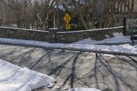 a road blocked by rock walls and trees in winter time in a town area with snow