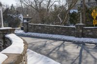 a road blocked by rock walls and trees in winter time in a town area with snow