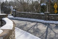 a road blocked by rock walls and trees in winter time in a town area with snow