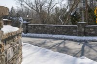 a road blocked by rock walls and trees in winter time in a town area with snow