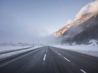 the highway is covered with snow on a gloom winter day in the mountainside area