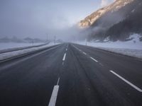 the highway is covered with snow on a gloom winter day in the mountainside area