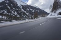 a snow covered mountain is in the background while a car drives down the road in a blur