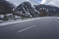 a snow covered mountain is in the background while a car drives down the road in a blur