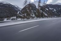 a snow covered mountain is in the background while a car drives down the road in a blur